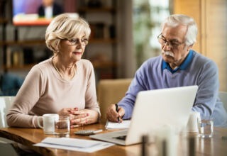 Mature couple using computer while planning their home budget.